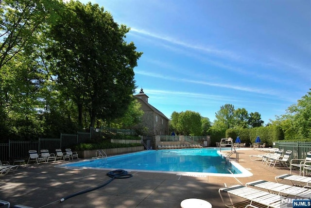 community pool with a patio and fence