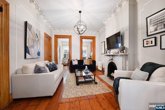 living room with hardwood / wood-style floors, radiator heating unit, rail lighting, and a chandelier