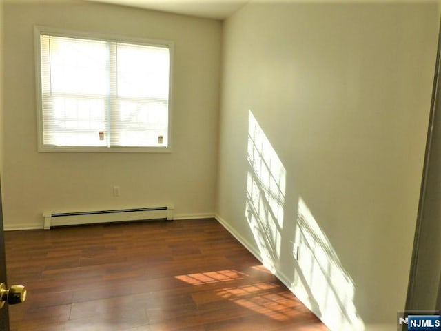 empty room with a baseboard heating unit and dark hardwood / wood-style flooring