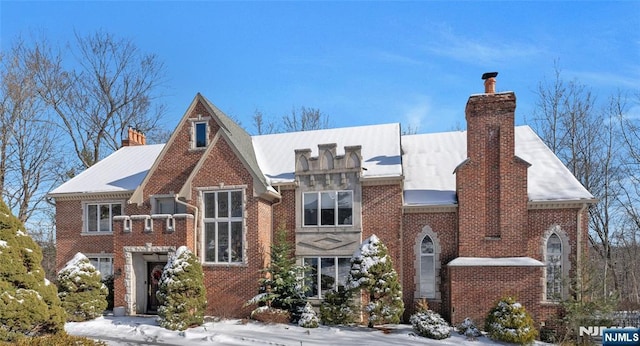 english style home with brick siding and a chimney