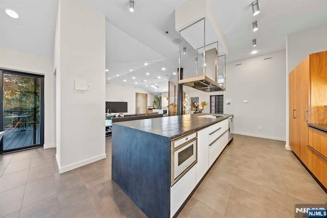 kitchen with white cabinetry, vaulted ceiling, and light tile patterned floors