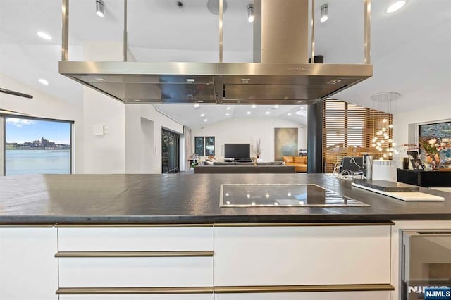 kitchen featuring a water view, white cabinetry, island exhaust hood, black electric stovetop, and beverage cooler