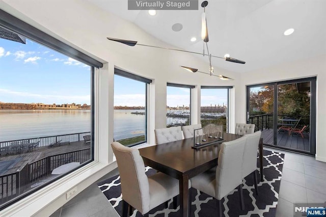 dining area featuring a water view, light tile patterned flooring, vaulted ceiling, and a notable chandelier