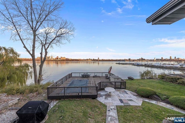 dock area featuring a deck with water view, a yard, and a patio area