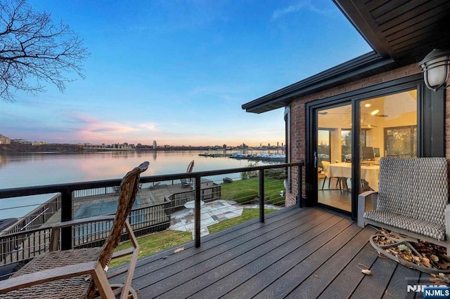 deck at dusk featuring a water view