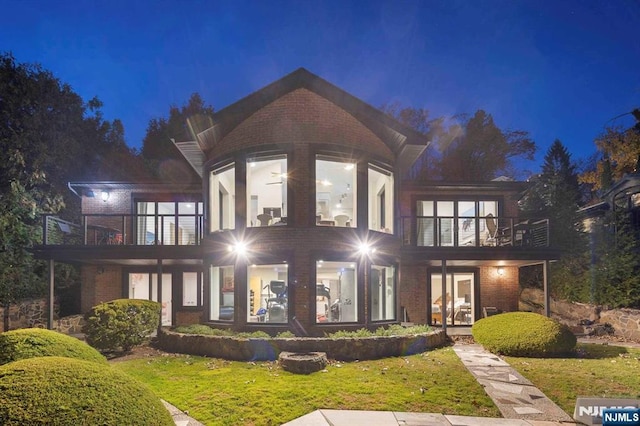 back house at night with a yard and a balcony