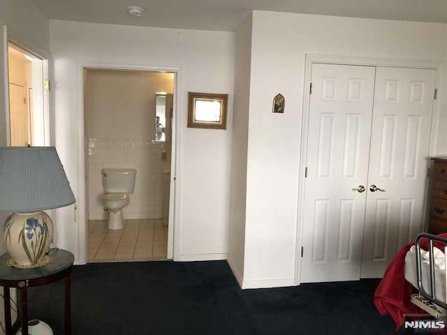 interior space featuring tile walls, toilet, and tile patterned floors