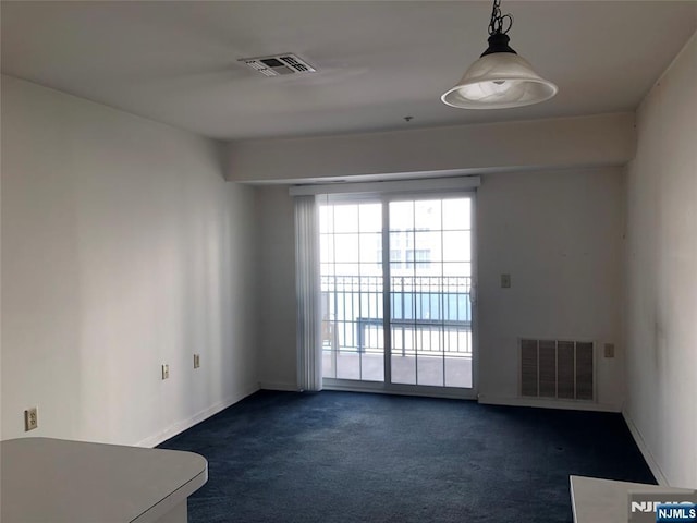 spare room with dark carpet, visible vents, and baseboards