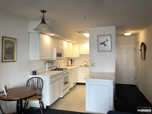 kitchen featuring pendant lighting, light countertops, white cabinetry, a sink, and white appliances