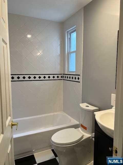 full bathroom featuring tiled shower / bath combo, vanity, and toilet