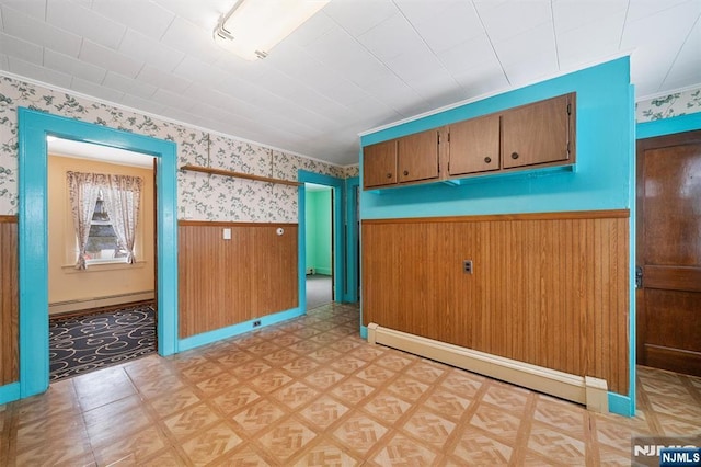 interior space featuring crown molding, wooden walls, and a baseboard heating unit