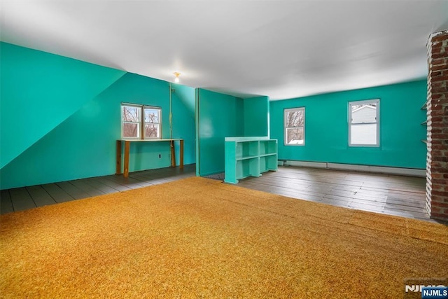 interior space featuring carpet floors, vaulted ceiling, and baseboard heating