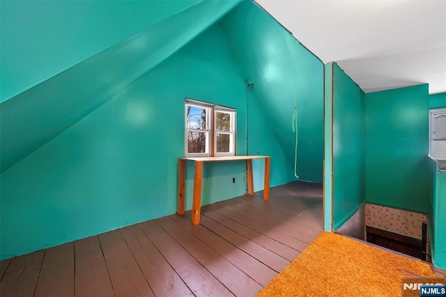 additional living space with wood-type flooring and vaulted ceiling