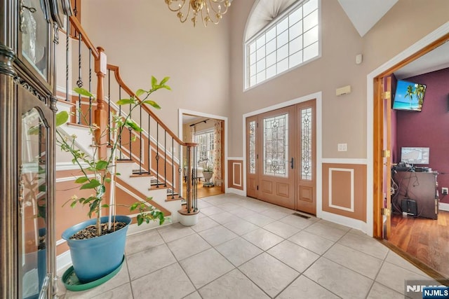 entrance foyer with light tile patterned flooring, a towering ceiling, and an inviting chandelier