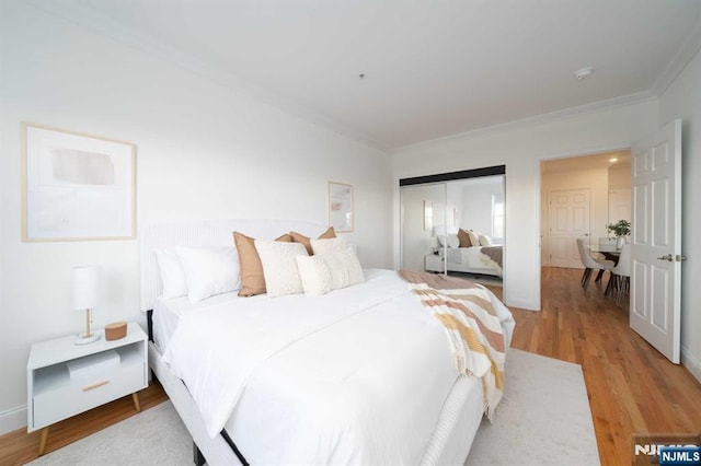 bedroom with ornamental molding, hardwood / wood-style floors, and a closet