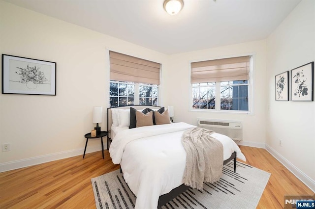 bedroom featuring a wall unit AC and light hardwood / wood-style floors