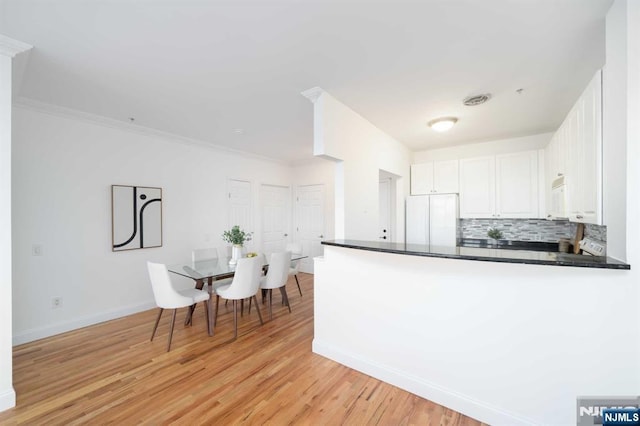 kitchen featuring backsplash, white cabinets, white appliances, crown molding, and light wood-type flooring