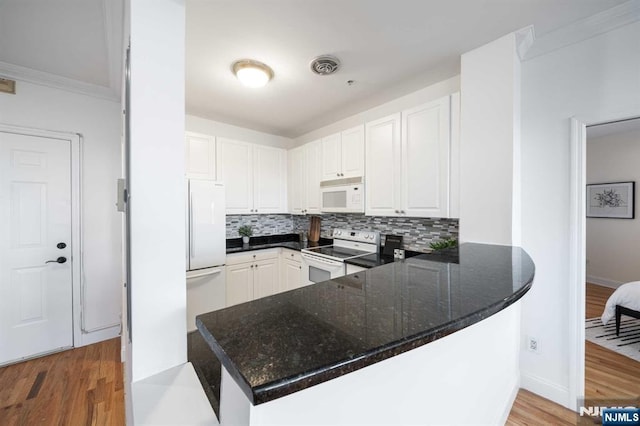 kitchen with light wood-type flooring, white cabinets, white appliances, and kitchen peninsula