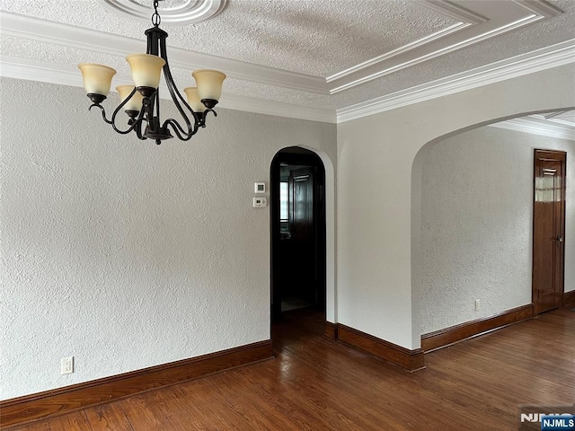 spare room with a textured ceiling, dark wood-type flooring, ornamental molding, and a chandelier