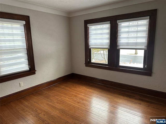 unfurnished room with hardwood / wood-style floors and a textured ceiling