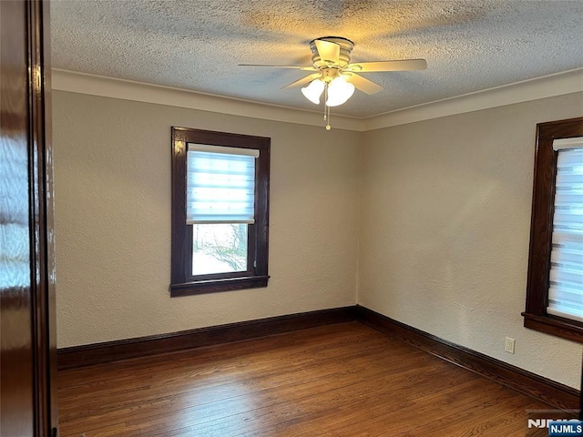 spare room featuring ceiling fan, dark hardwood / wood-style floors, and a textured ceiling