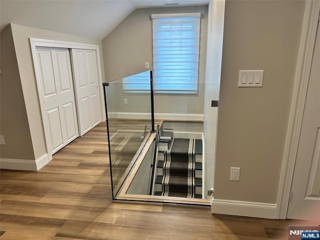 staircase featuring lofted ceiling and wood-type flooring