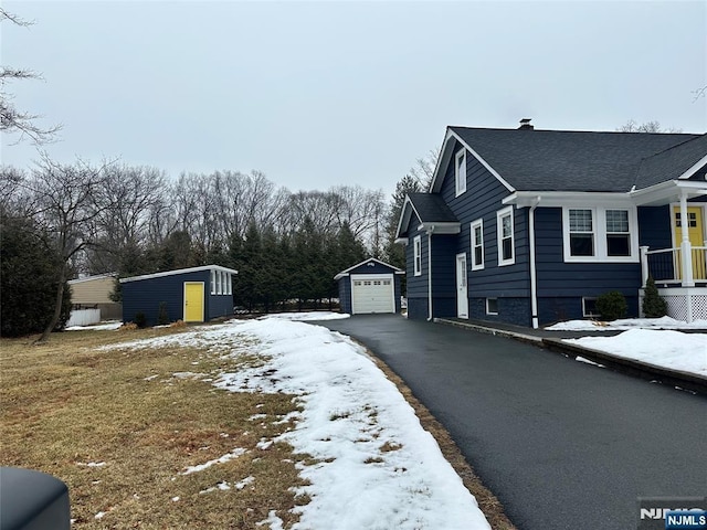 view of snow covered exterior featuring a storage shed and a garage