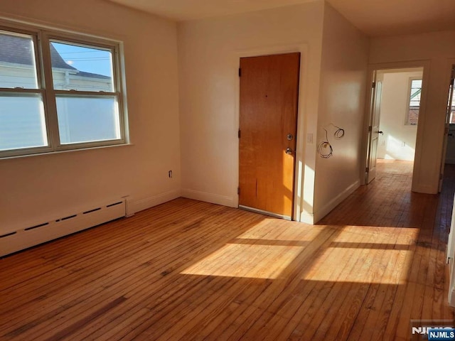 spare room featuring a baseboard radiator and hardwood / wood-style floors