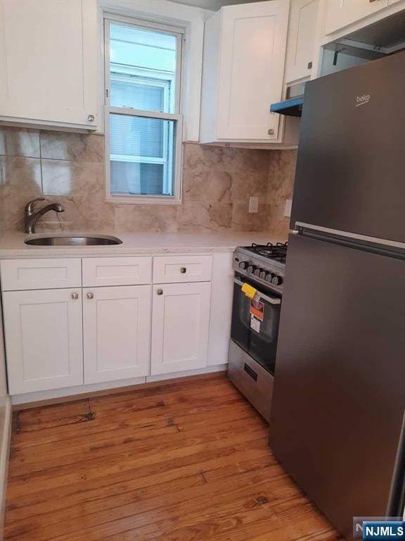 kitchen featuring white cabinetry, appliances with stainless steel finishes, sink, and light hardwood / wood-style flooring