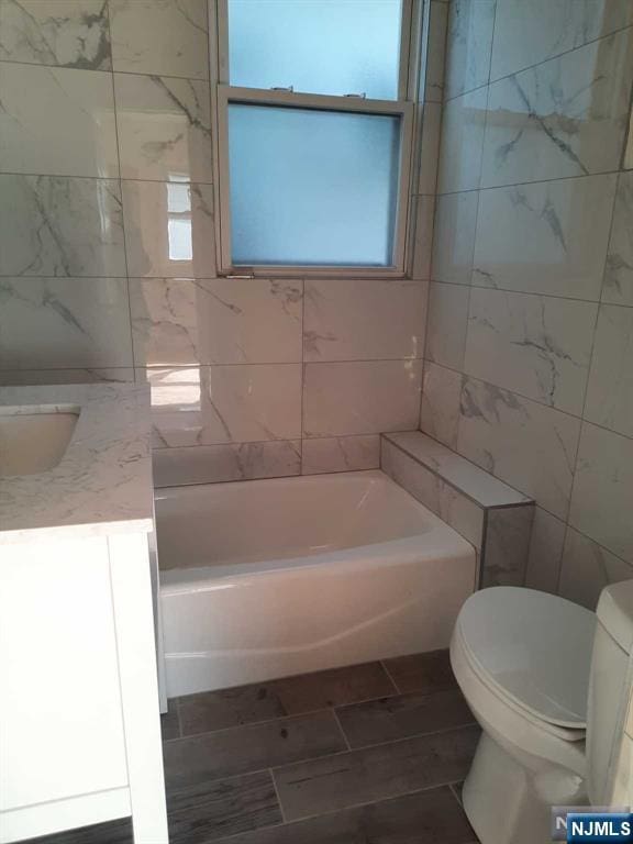 bathroom with vanity, tile walls, and toilet