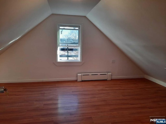 additional living space with wood-type flooring, vaulted ceiling, and baseboard heating