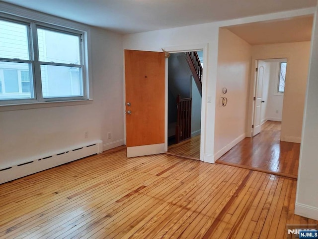 empty room with a baseboard radiator and light hardwood / wood-style floors