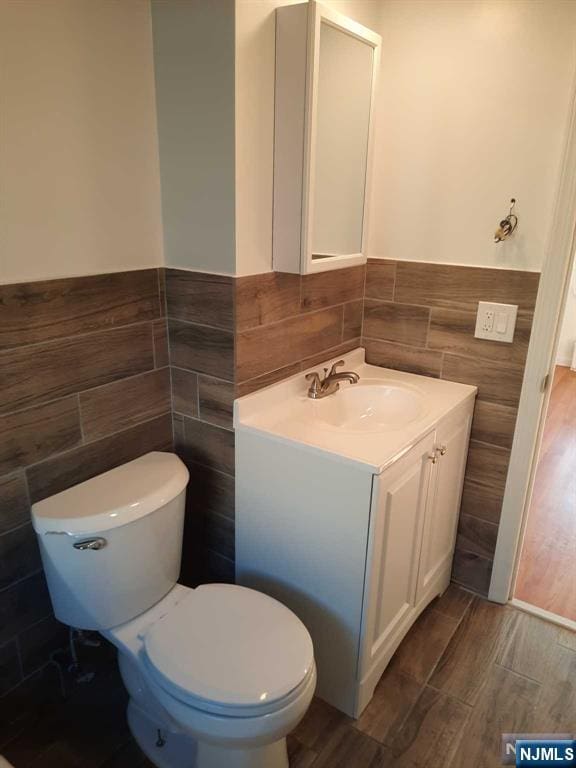 bathroom featuring tile walls, vanity, hardwood / wood-style floors, and toilet