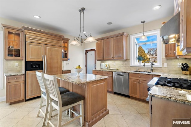 kitchen with appliances with stainless steel finishes, glass insert cabinets, a kitchen island, and extractor fan