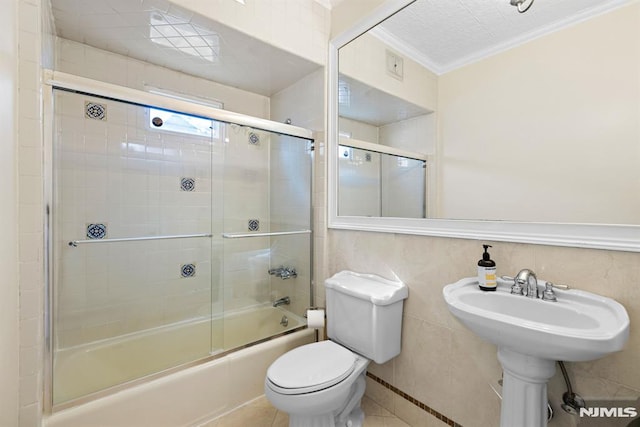 full bathroom featuring toilet, tile patterned flooring, bath / shower combo with glass door, and ornamental molding