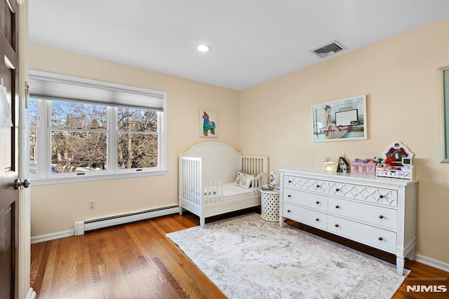 bedroom with recessed lighting, visible vents, baseboard heating, wood finished floors, and baseboards