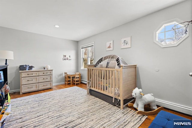 bedroom featuring recessed lighting, light wood-style flooring, baseboards, and a baseboard radiator