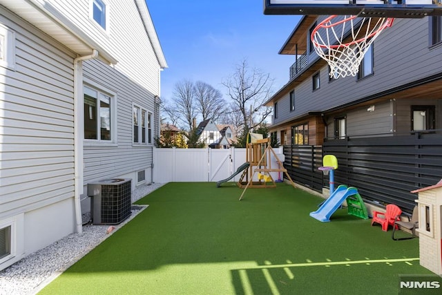 view of yard featuring a fenced backyard, a playground, and central AC unit