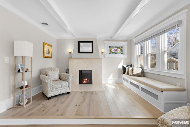 living area featuring a premium fireplace, beamed ceiling, wood finished floors, and baseboards