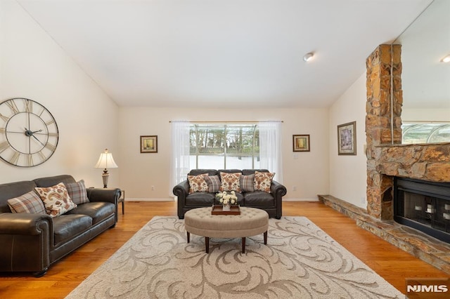 living room with lofted ceiling, a fireplace, and light wood-type flooring