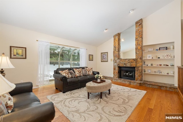 living room featuring lofted ceiling, a fireplace, and light hardwood / wood-style flooring