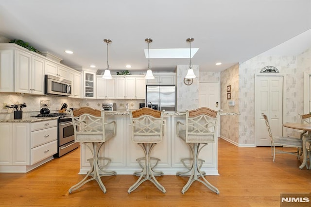 kitchen with a center island, stainless steel appliances, a kitchen breakfast bar, and decorative light fixtures