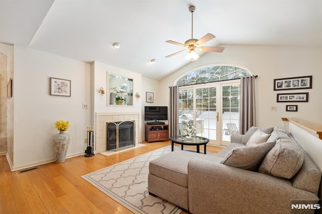 living room featuring french doors, lofted ceiling, ceiling fan, a fireplace, and light hardwood / wood-style floors