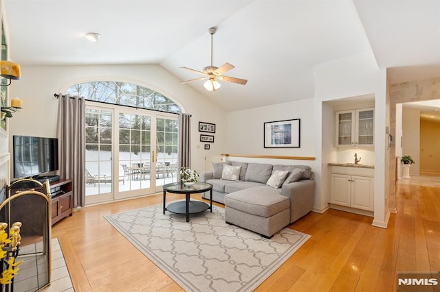 living room featuring lofted ceiling, sink, light hardwood / wood-style floors, and ceiling fan