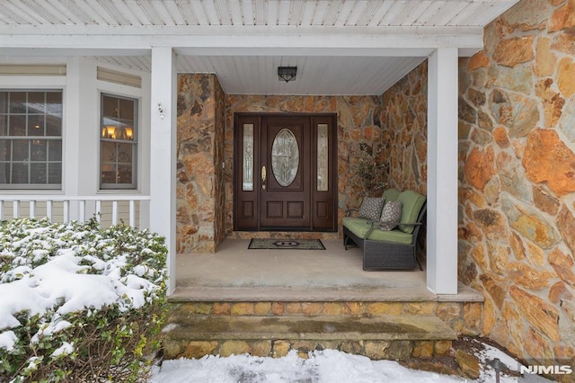 snow covered property entrance with a porch