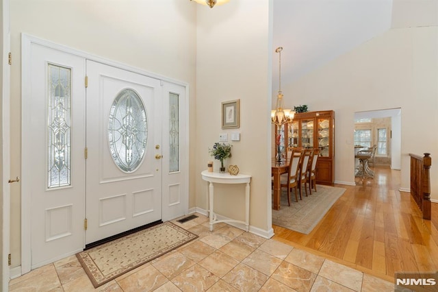 foyer with high vaulted ceiling, light hardwood / wood-style floors, and a chandelier