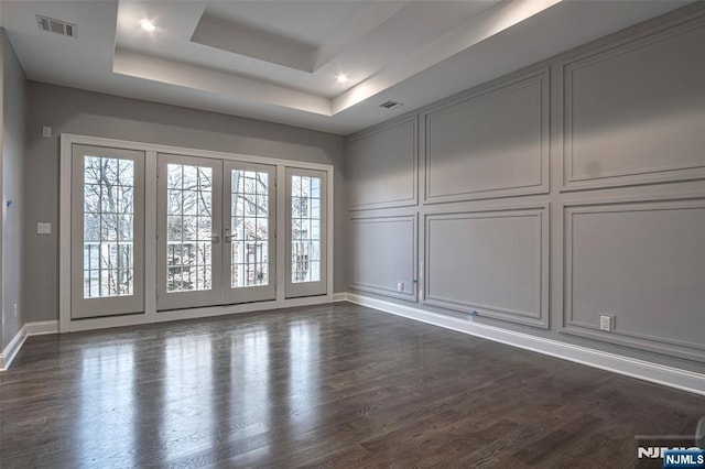 empty room with a raised ceiling and dark wood-type flooring