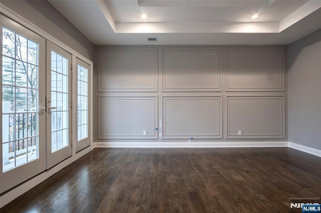 interior space with dark wood-type flooring, a raised ceiling, and french doors