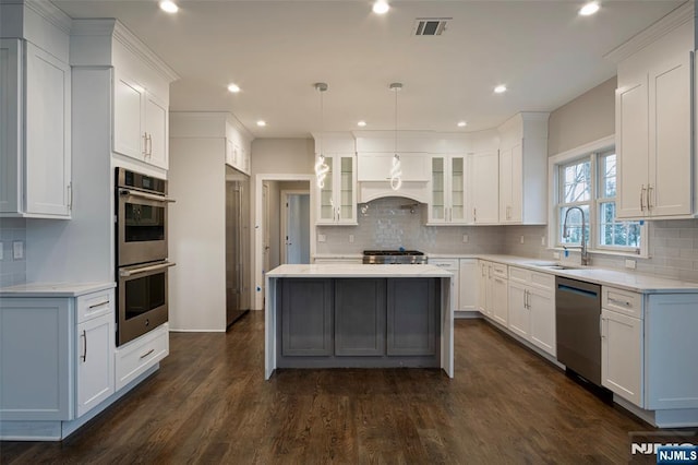 kitchen featuring stainless steel appliances, sink, pendant lighting, and white cabinets