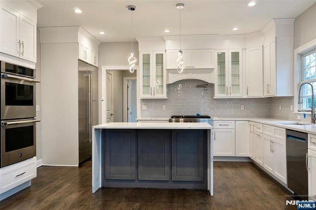 kitchen featuring decorative light fixtures, white cabinetry, sink, dishwashing machine, and stainless steel double oven